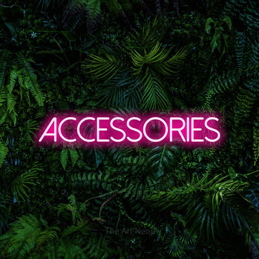 Hot pink LED neon sign reading "Accessories" against a dense tropical foliage wall
