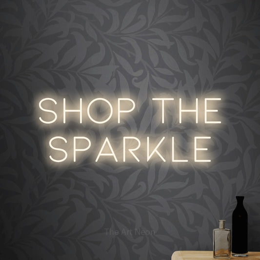 Warm white LED neon sign reading "Shop the Sparkle" against light grey floral wallpaper