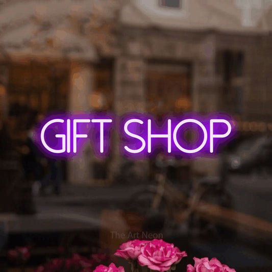 Purple LED neon sign reading "Gift Shop" in a softly blurred café interior