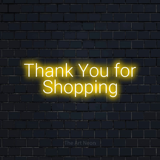 Yellow LED neon sign reading "Thank You for Shopping" against a dark navy brick wall