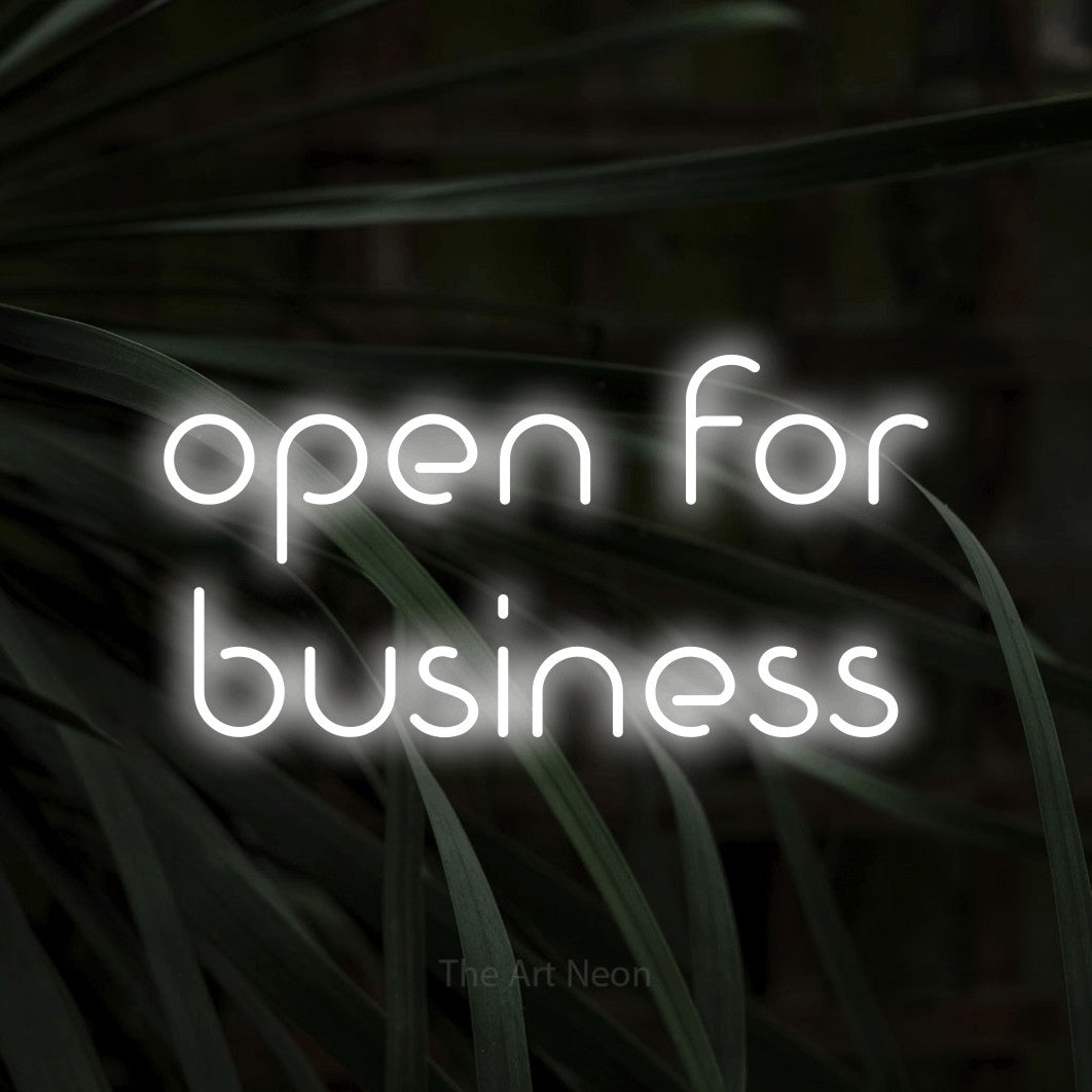 Cool white LED neon sign reading "Open for Business" against dark tropical leaves