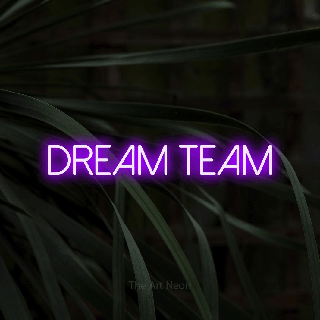 Purple LED neon sign reading "Dream Team" against dark tropical leaves for office décor