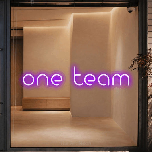 Purple LED neon sign reading "One Team" against a warm beige alcove wall for office décor
