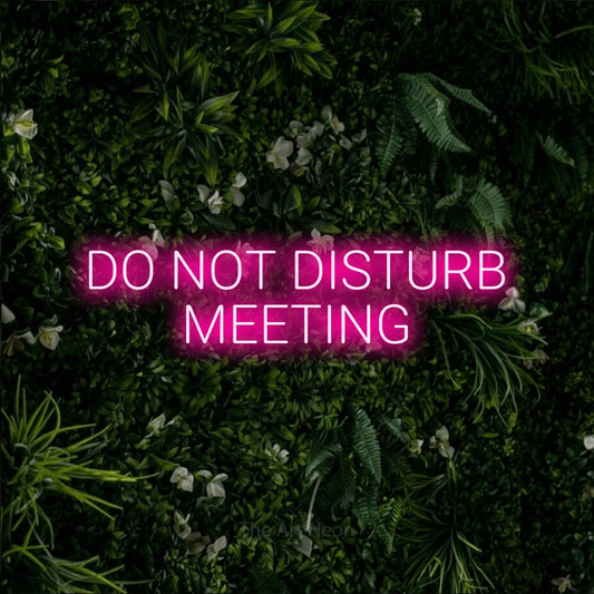 Hot pink LED neon sign reading "Do Not Disturb Meeting" against a leafy green wall for office décor