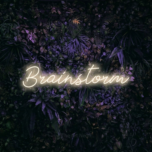 Warm white script-style LED neon sign reading "Brainstorm" against a purple floral wall for office décor