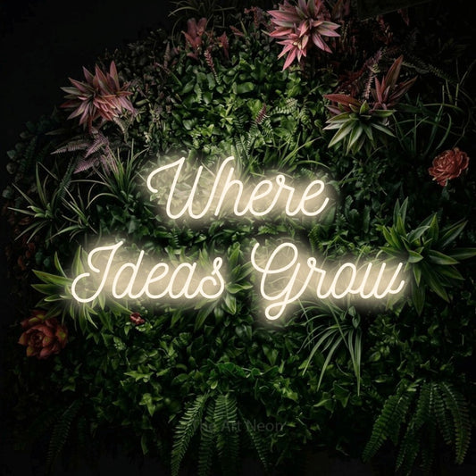 Warm white script-style LED neon sign reading "Where Ideas Grow" against a flowering garden wall for office décor