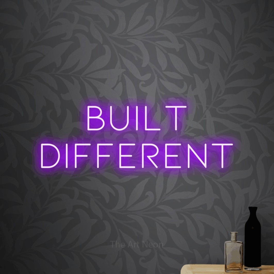 Enseigne néon à DEL à lumière violette, affichant « Built Different » sur un papier peint floral gris pâle, pour décorer un bureau
