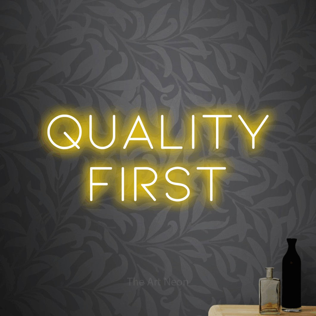 Yellow LED neon sign reading "Quality First" against light grey floral wallpaper for office décor