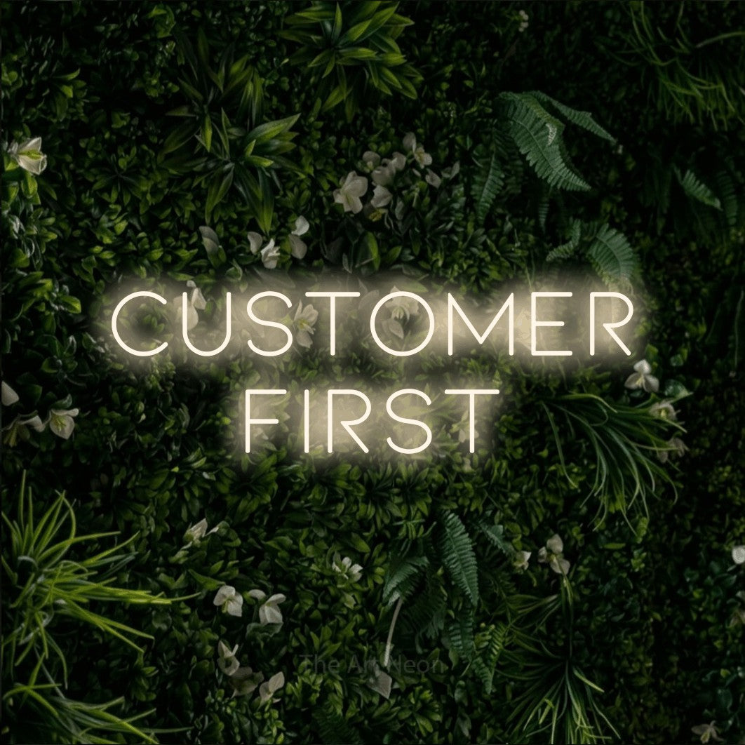 Warm white LED neon sign reading "Customer First" against a leafy green wall for office décor
