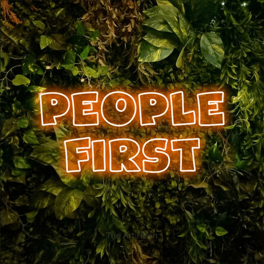 Enseigne néon à DEL à lumière orange, de style contour, affichant « People First » sur un mur texturé de mousse et de feuillage, pour décorer un bureau