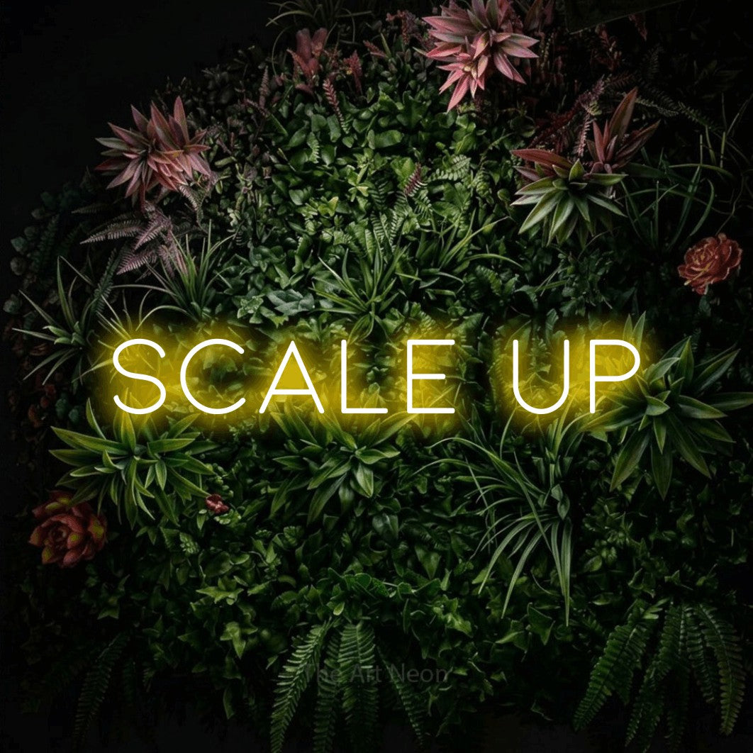 Yellow LED neon sign reading "Scale Up" against a flowering garden wall for office décor
