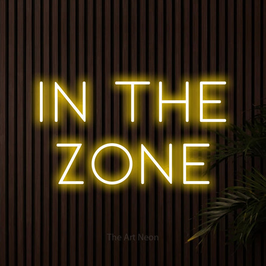 Yellow LED neon sign reading "In the Zone" against dark wooden slats for office décor