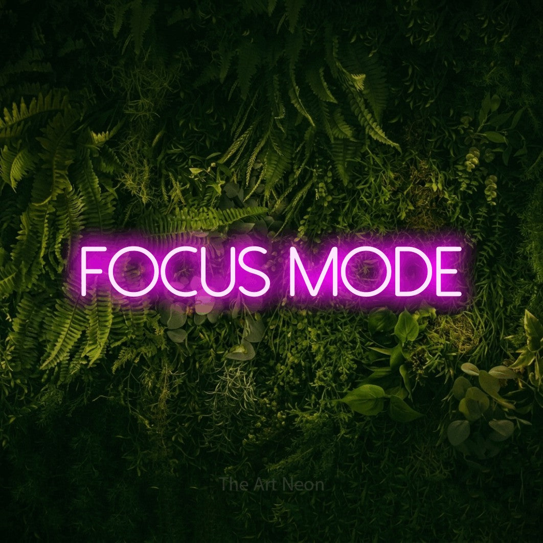 Pink LED neon sign reading "Focus Mode" against a moss-covered green wall for office décor