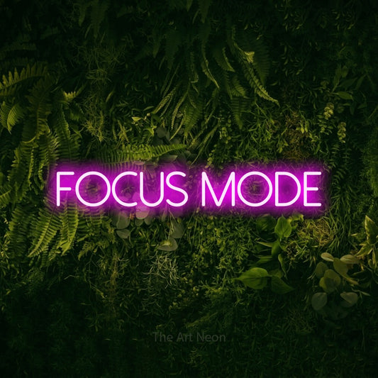 Pink LED neon sign reading "Focus Mode" against a moss-covered green wall for office décor