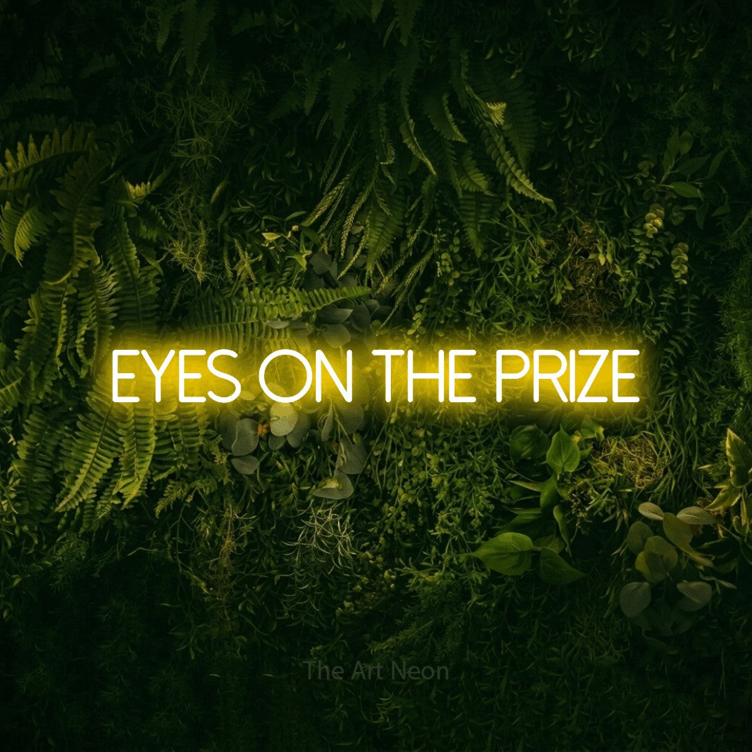 Yellow LED neon sign reading "Eyes on the Prize" against a moss-covered green wall for office décor