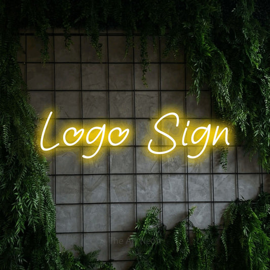 Yellow LED neon sign reading "Logo" against a green grid wall with foliage for office décor