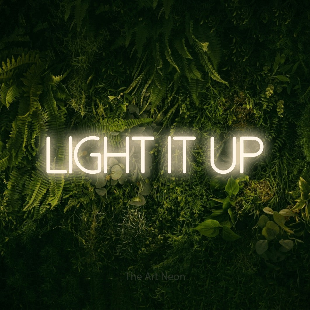 Warm white LED neon sign reading "Light It Up" against a moss-covered green wall for office décor
