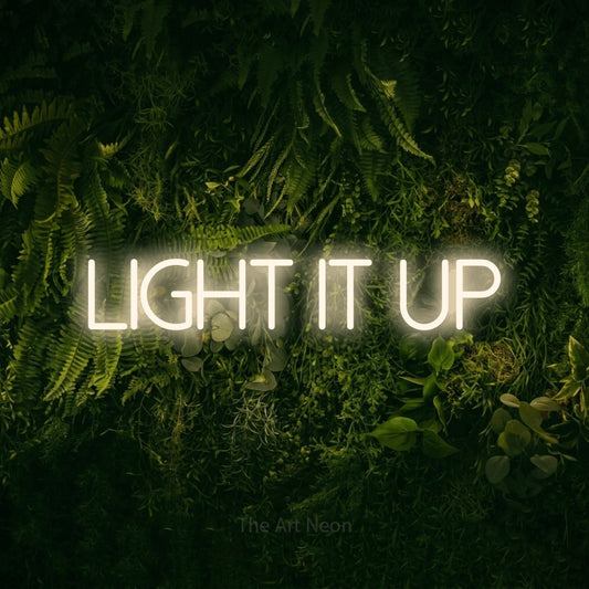 Warm white LED neon sign reading "Light It Up" against a moss-covered green wall for office décor