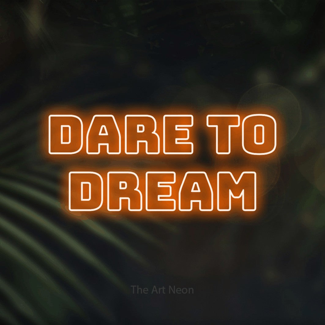Orange outline-style LED neon sign reading "Dare to Dream" against dark blurred palm leaves for office décor