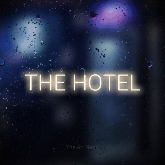 Warm white LED neon sign reading "The Hotel" against a dark blue bokeh background for hotel décor