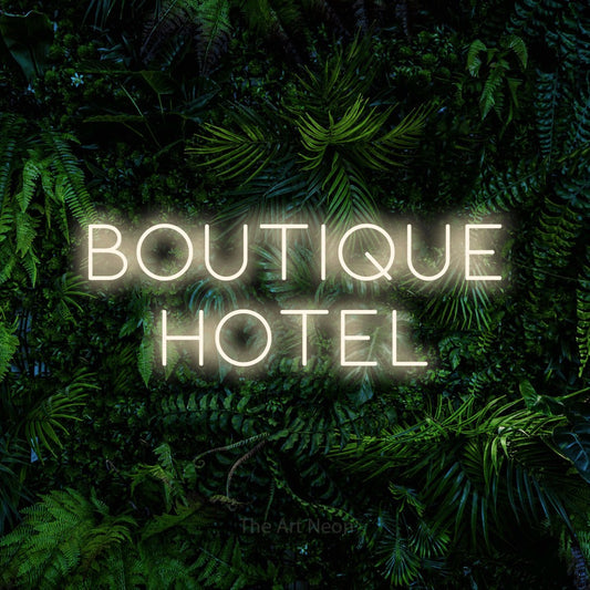 Warm white LED neon sign reading "Boutique Hotel" against a dense tropical foliage wall for hotel décor