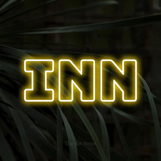 Yellow outline-style LED neon sign reading "Inn" against dark tropical leaves for hotel décor