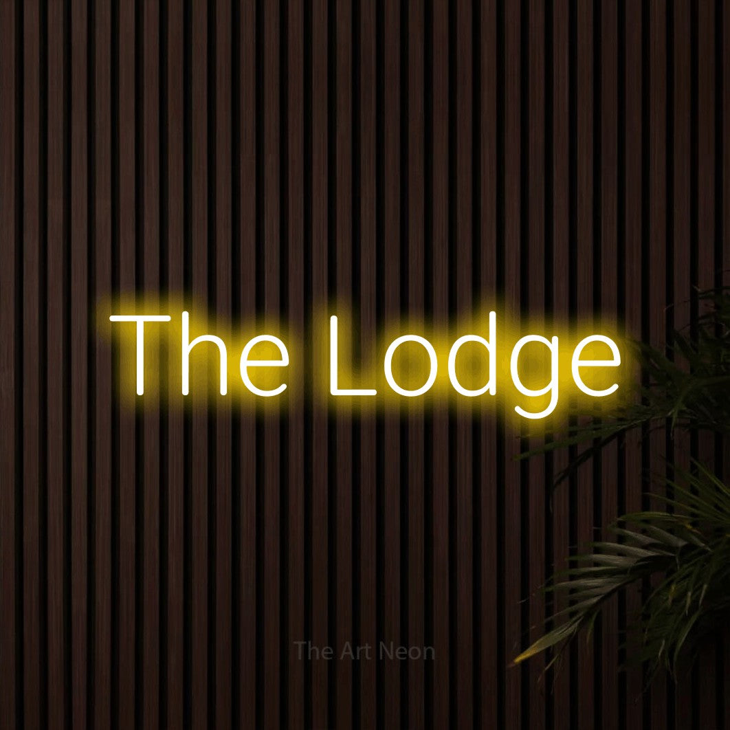 Yellow LED neon sign reading "The Lodge" against dark wooden slats for hotel décor