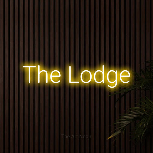 Yellow LED neon sign reading "The Lodge" against dark wooden slats for hotel décor