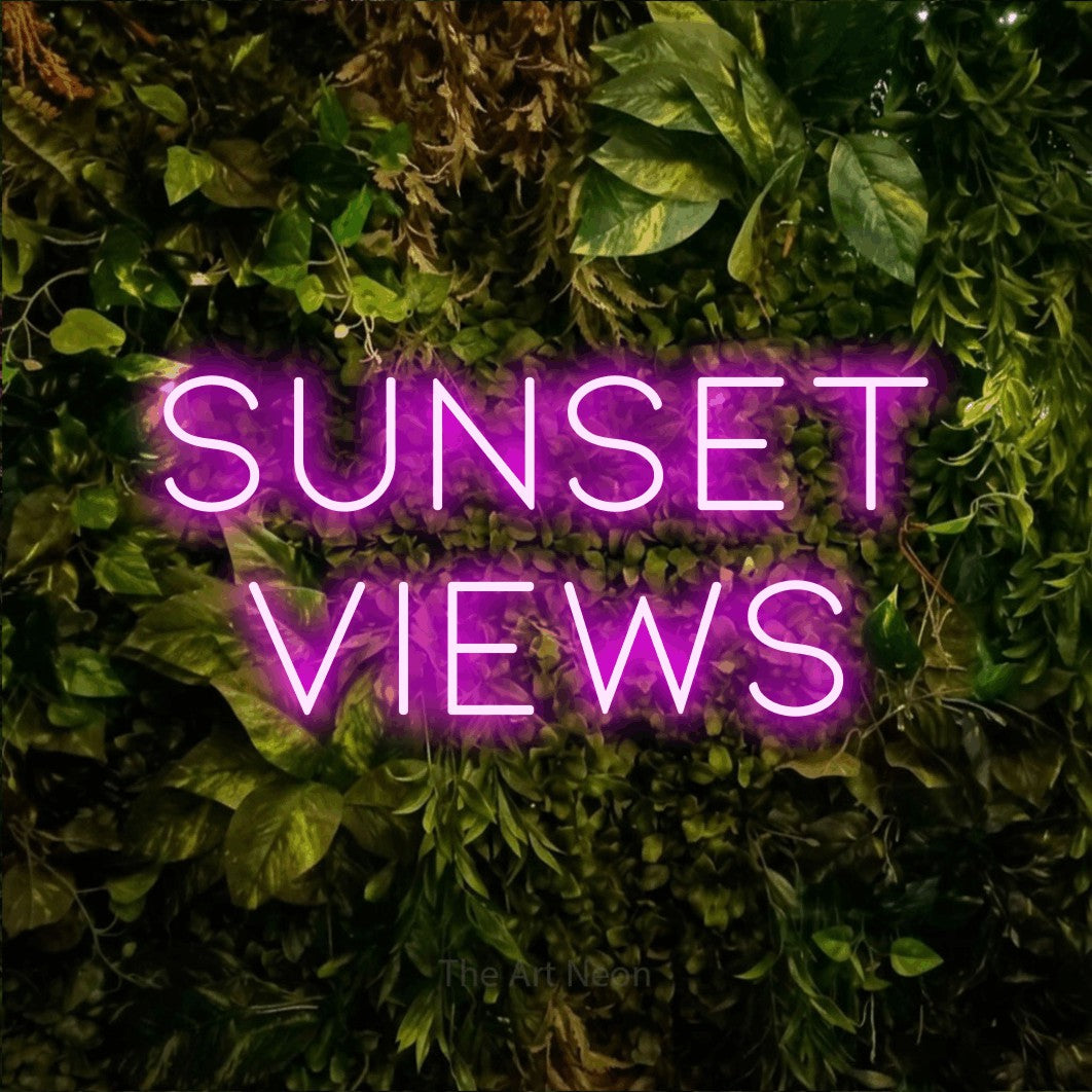 Pink LED neon sign reading "Sunset Views" against a textured moss and foliage wall for hotel décor