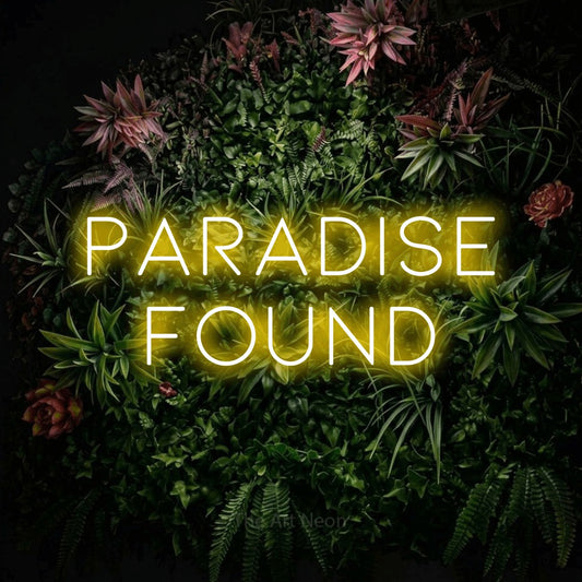 Yellow LED neon sign reading "Paradise Found" against a flowering garden wall for hotel décor