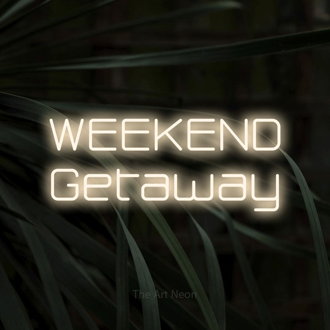 Warm white LED neon sign reading "Weekend Getaway" against dark tropical leaves for hotel décor