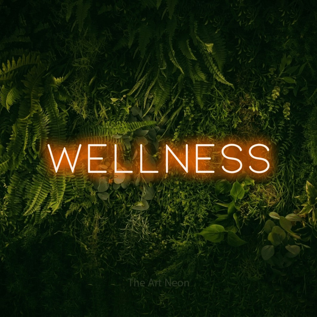 Orange LED neon sign reading "Wellness" against a moss-covered green wall for hotel décor