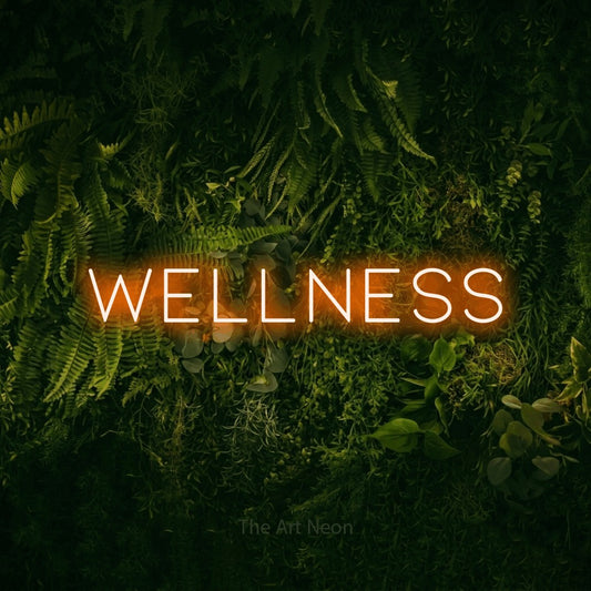 Orange LED neon sign reading "Wellness" against a moss-covered green wall for hotel décor
