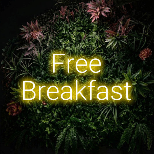 Yellow LED neon sign reading "Free Breakfast" against a flowering garden wall for hotel décor