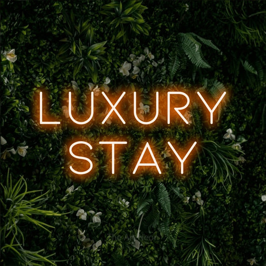 Orange LED neon sign reading "Luxury Stay" against a leafy green wall for hotel décor