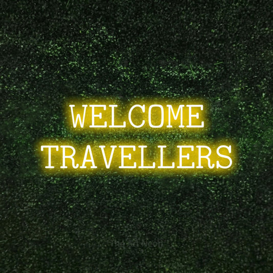 Yellow LED neon sign reading "Welcome Travellers" against a textured green moss wall for hotel décor