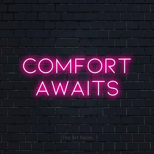 Hot pink LED neon sign reading "Comfort Awaits" against a dark navy brick wall for hotel décor