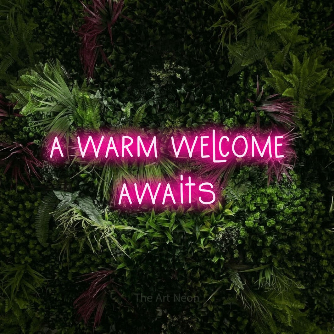 Hot pink LED neon sign reading "A Warm Welcome Awaits" against a lush garden wall with pink flowers for hotel décor