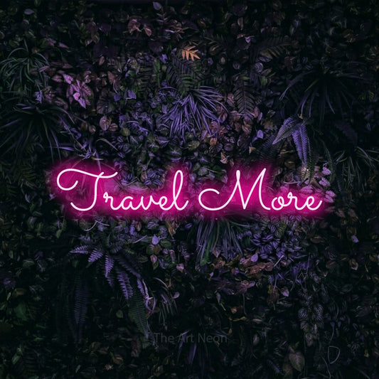Hot pink LED neon sign reading "Travel More" against a purple floral wall for hotel décor