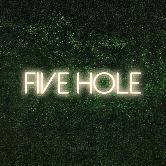 Enseigne néon à DEL à lumière blanche chaude, affichant « Five Hole » sur un mur texturé de mousse verte