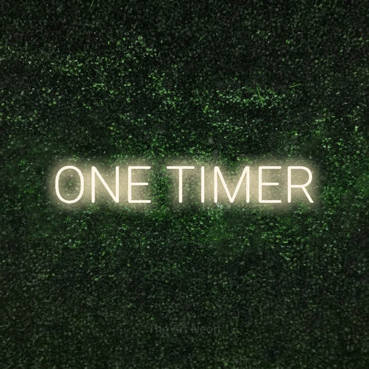 Warm white LED neon sign reading "One Timer" against a textured green moss wall