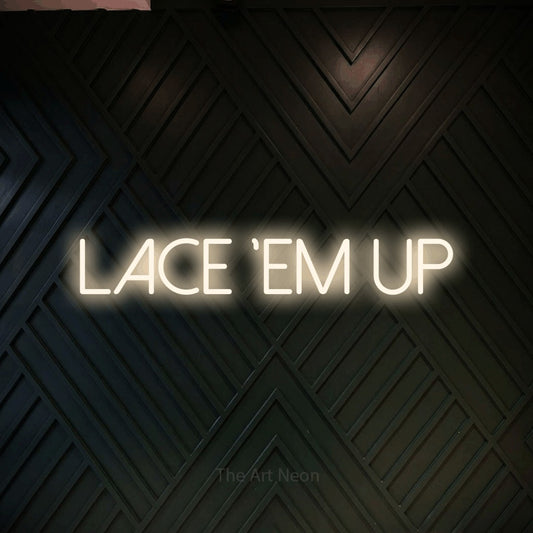 Warm white LED neon sign reading "Lace 'Em Up" against a dark geometric wood wall
