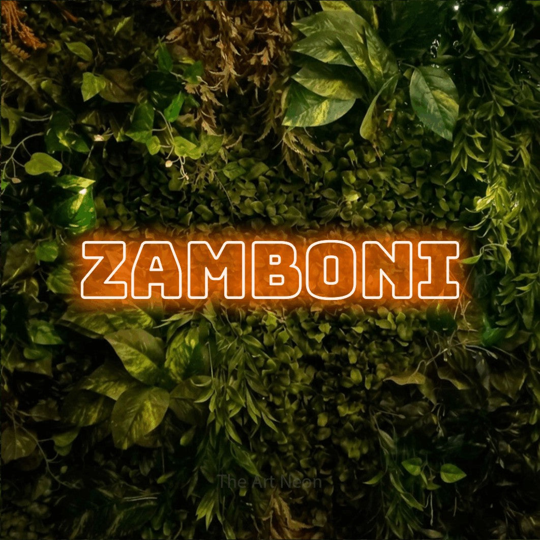 Orange outline-style LED neon sign reading "Zamboni" against a textured moss and foliage wall