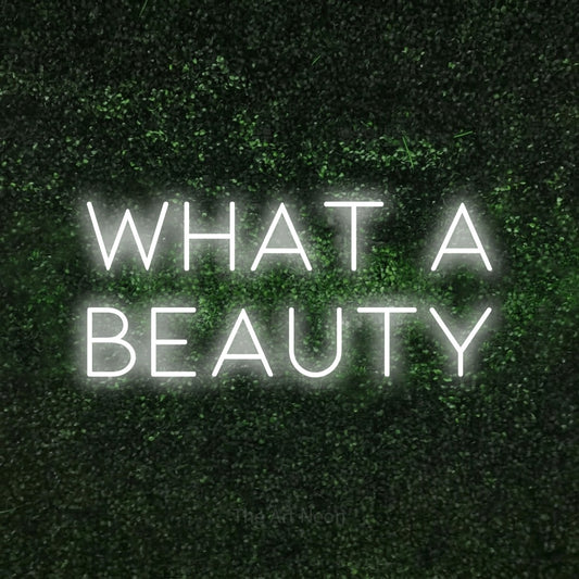 Enseigne néon à DEL à lumière blanche froide, affichant « What a Beauty » sur un mur texturé de mousse verte