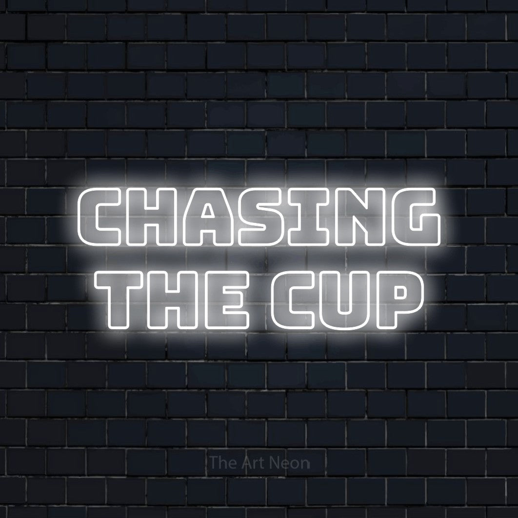 Cool white outline-style LED neon sign reading "Chasing the Cup" against a dark navy brick wall