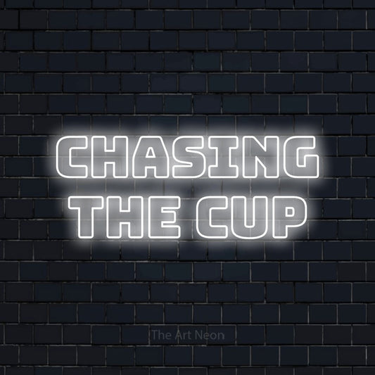 Cool white outline-style LED neon sign reading "Chasing the Cup" against a dark navy brick wall