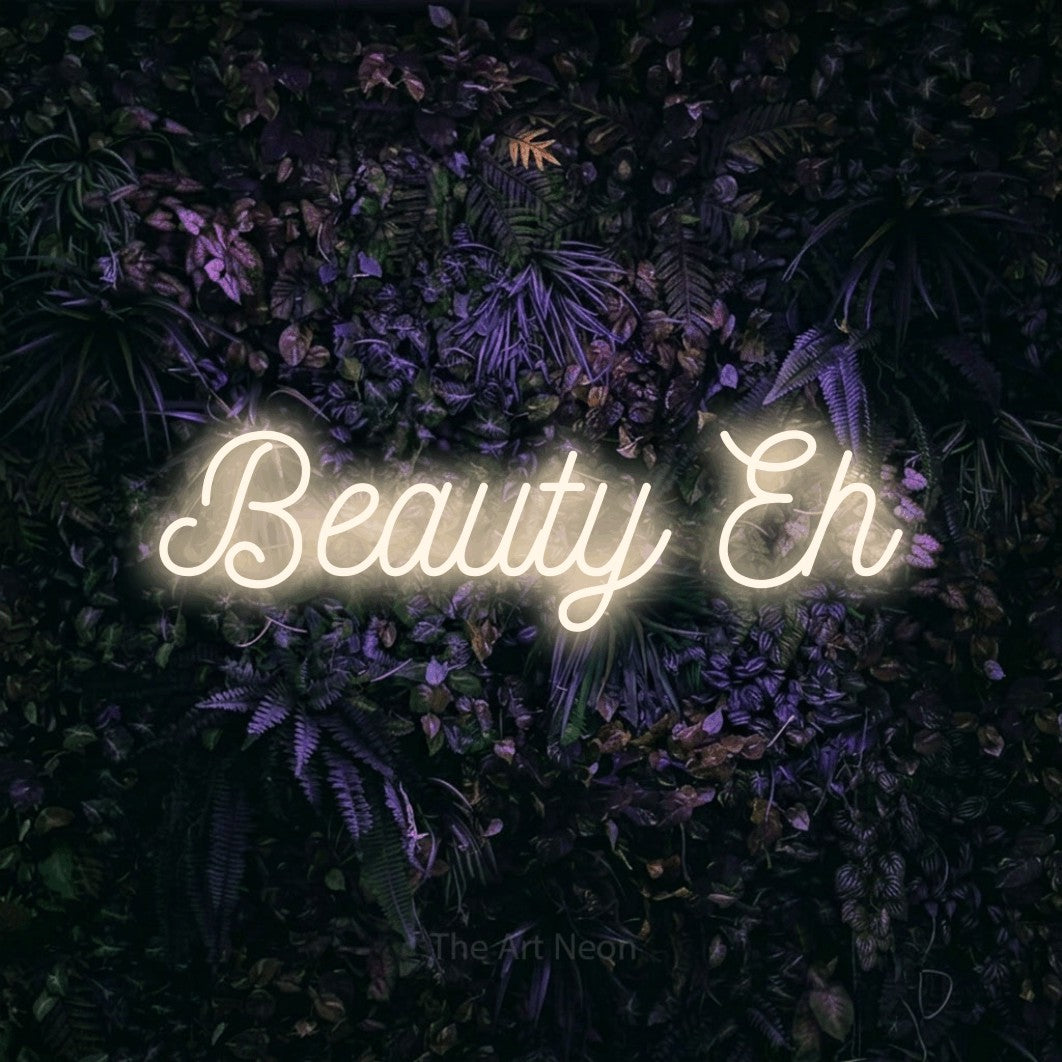 Warm white script-style LED neon sign reading "Beauty Eh" against a purple floral wall