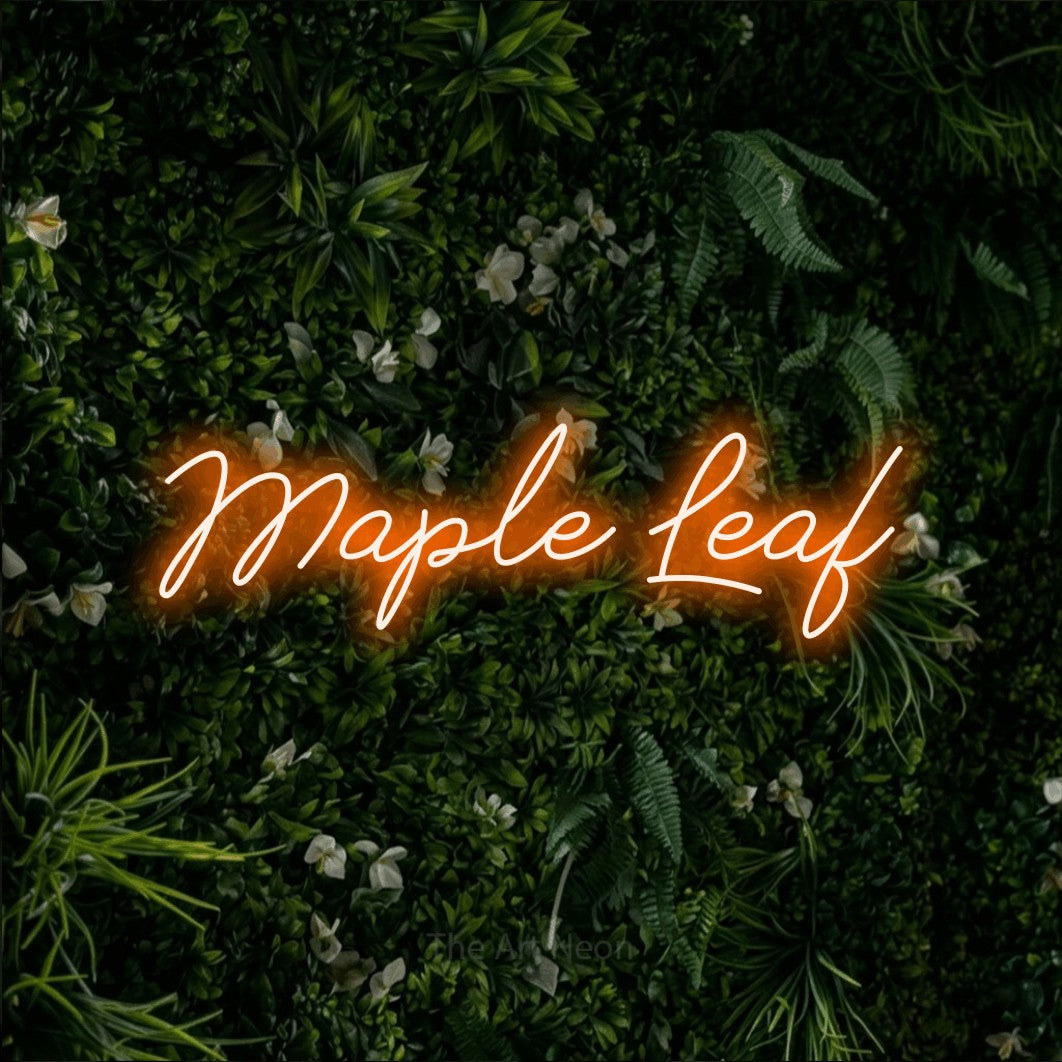 Orange script-style LED neon sign reading "Maple Leaf" against a leafy green wall