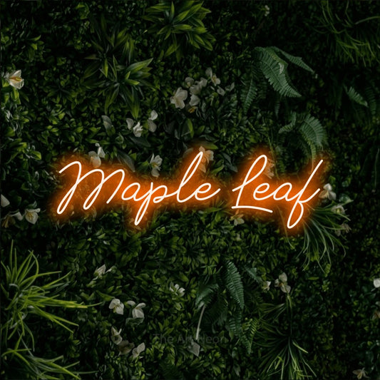 Enseigne néon à DEL à lumière orange, de style manuscrit, affichant « Maple Leaf » sur un mur de feuillage vert