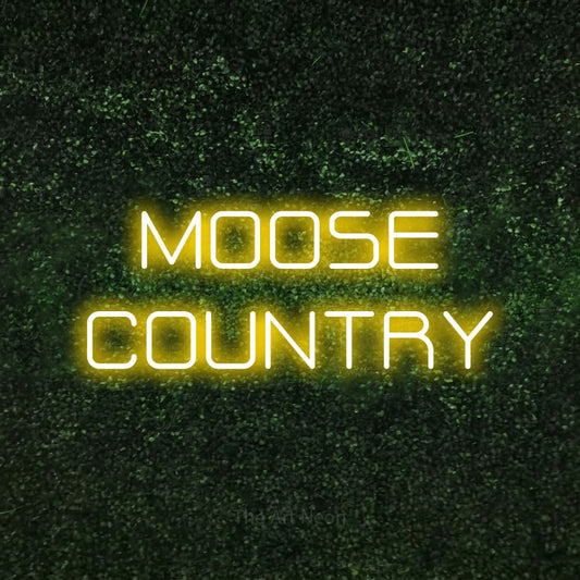 Enseigne néon à DEL à lumière jaune, affichant « Moose Country » sur un mur texturé de mousse verte